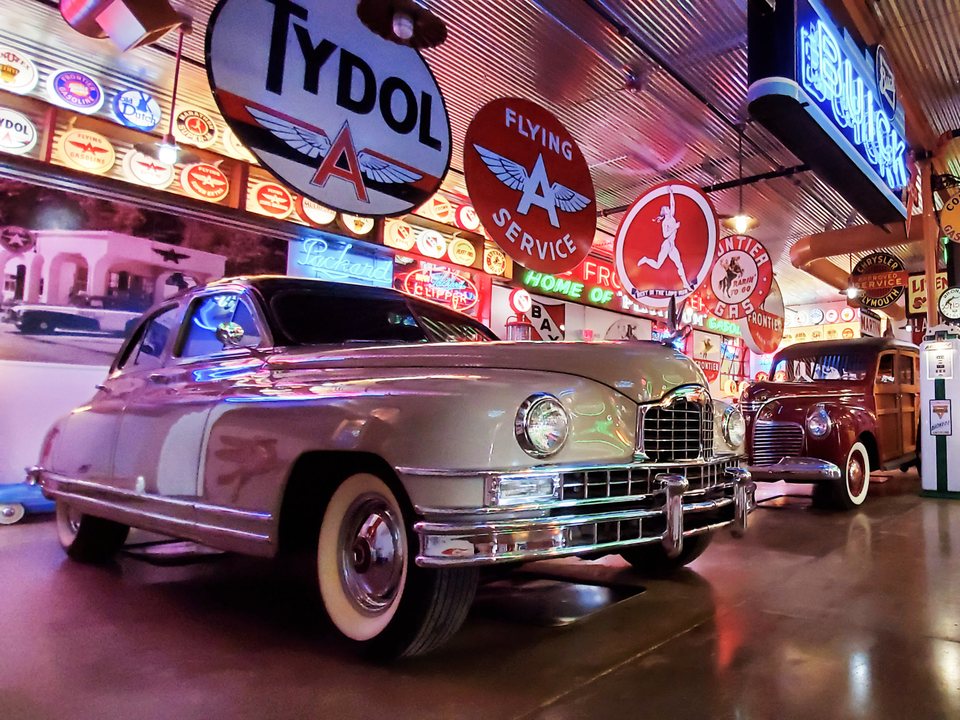 Classic car surrounded by neon and automotive displays inside Frontier Auto Museum in Gillette