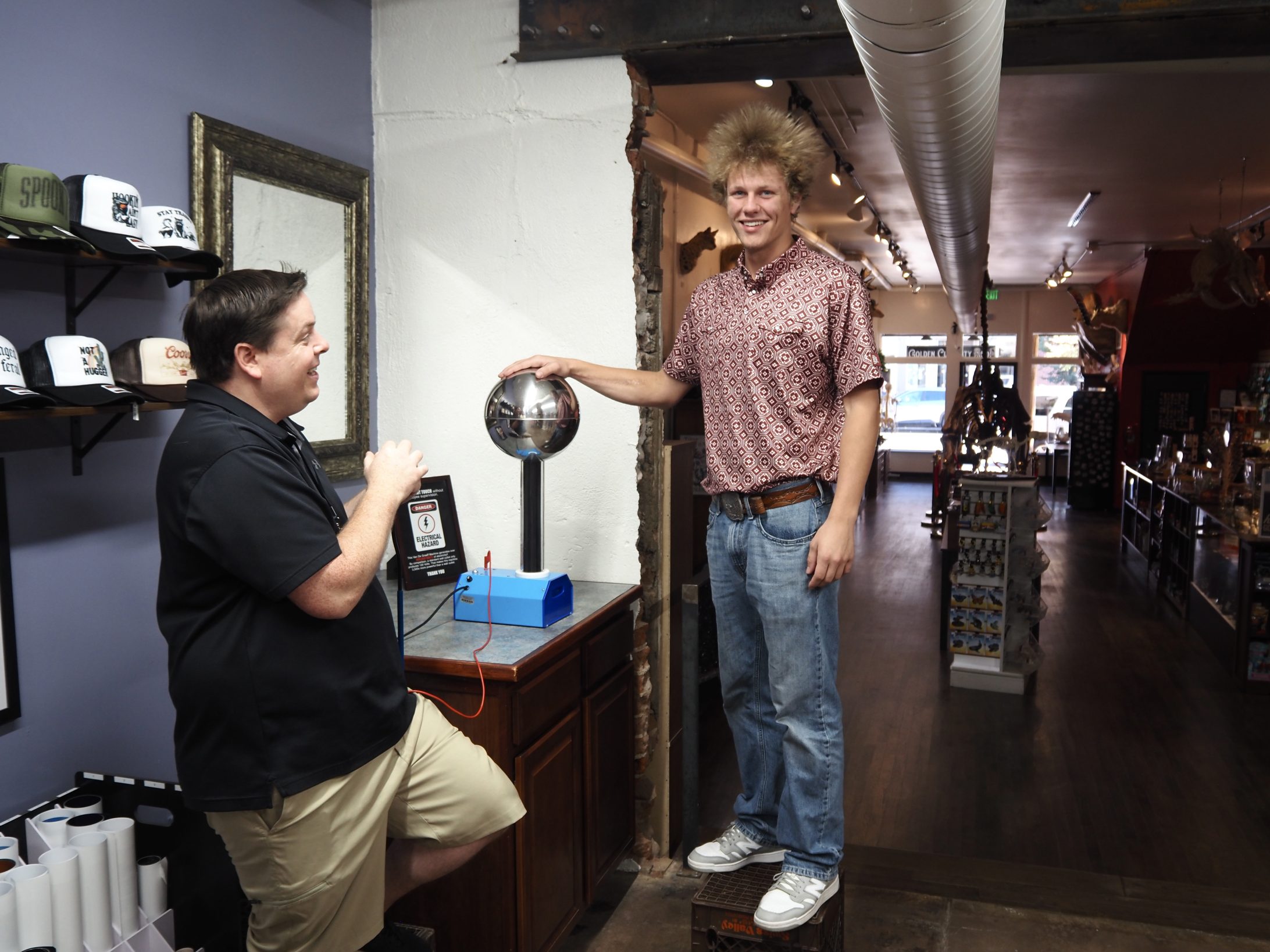 Interior of the new downtown Golden Curiosity Shop with natural-history displays and a Van de Graaff demonstration