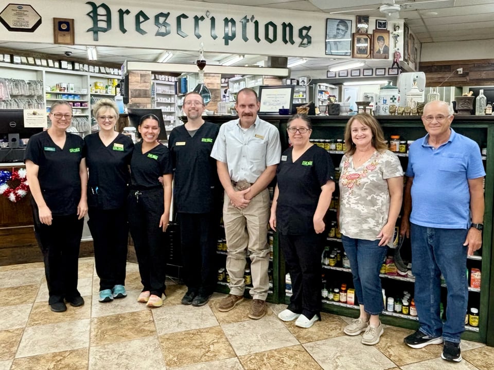 Owl Drug Store staff in front of the historic-style prescription counter in Coleman