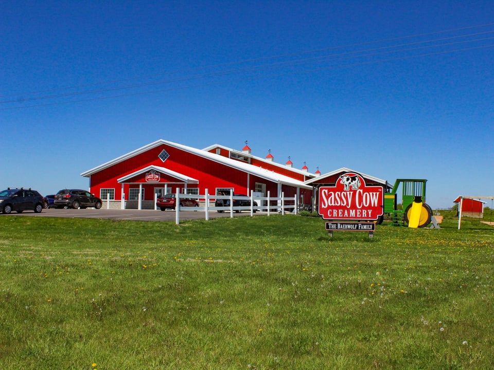 The red Sassy Cow Creamery building and roadside sign at the Columbus farmstead