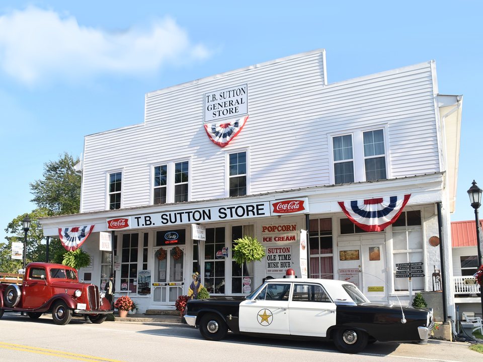 White T.B. Sutton General Store storefront in Granville with vintage vehicles and ice-cream signs
