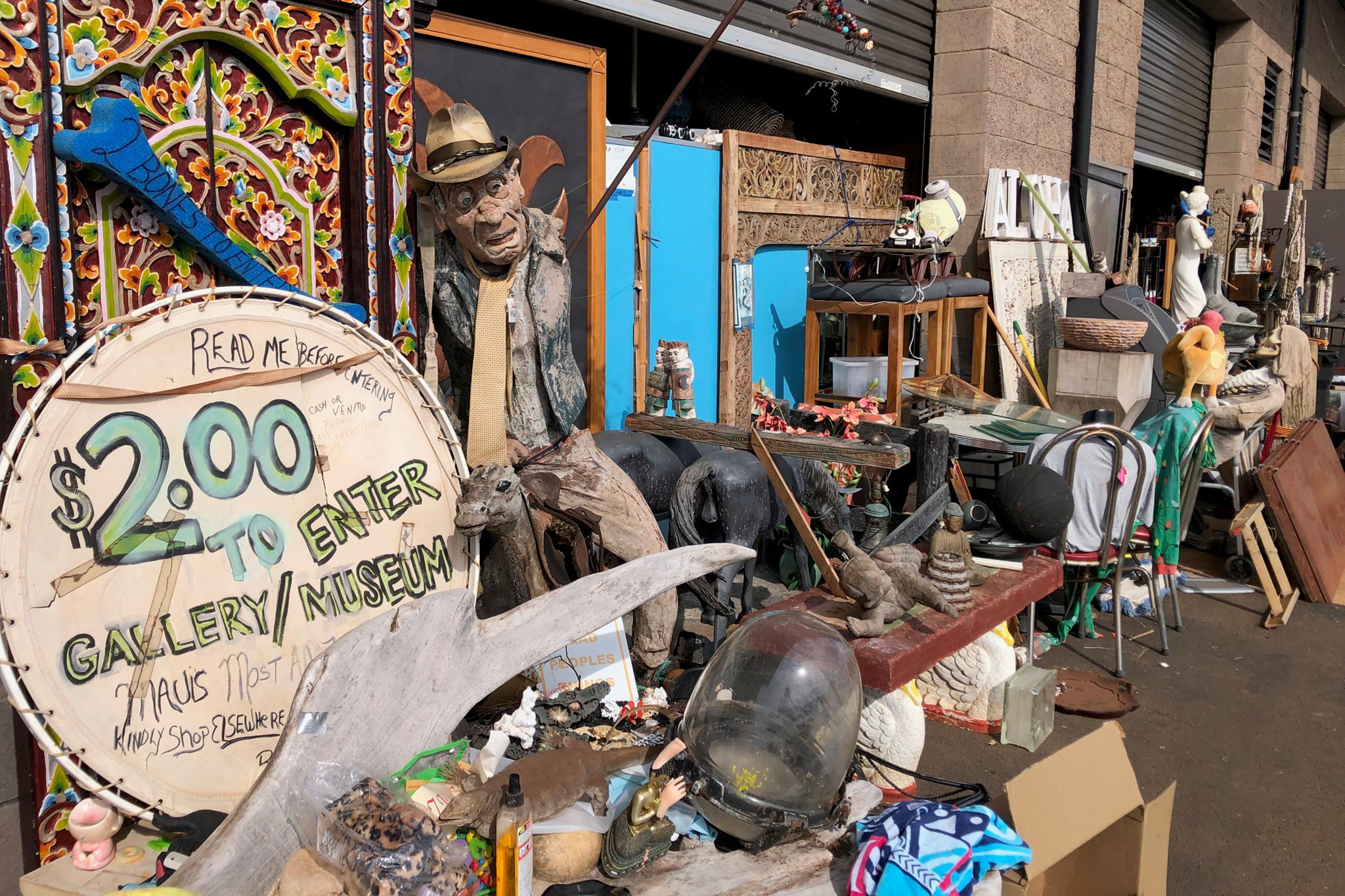 Outdoor display at the 170 Lauo Loop Kahului warehouse with large estate objects and the two-dollar gallery and museum sign